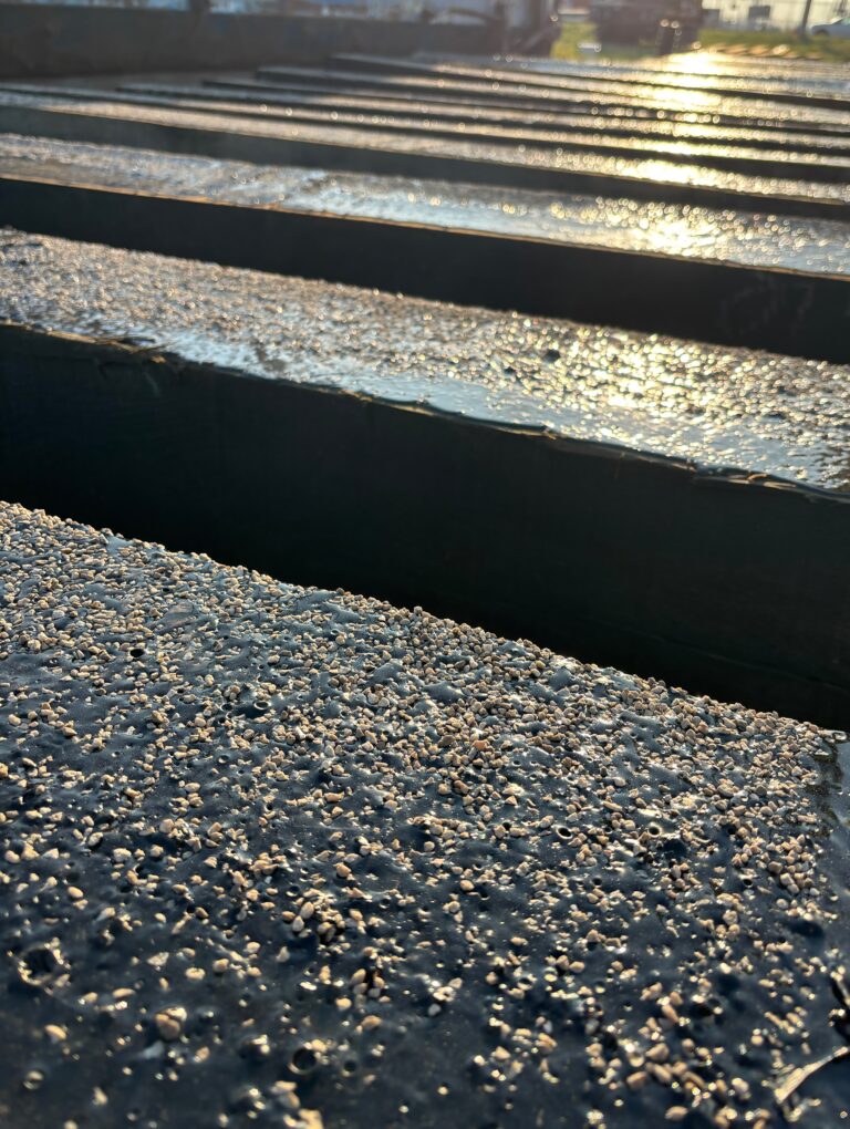 The asphalt coating is topped with aggregate (small rocks) for slip resistance.